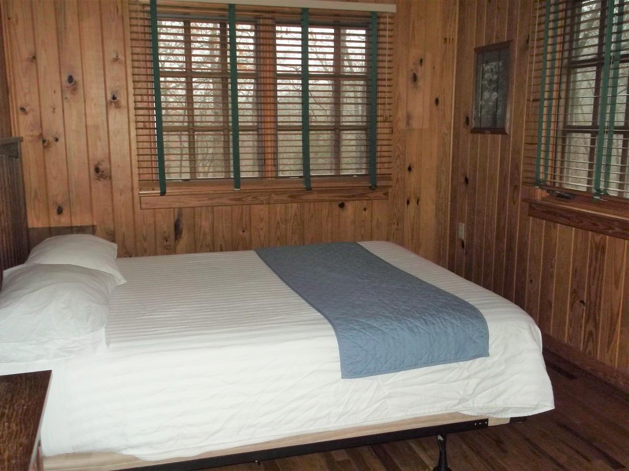 View of one of the bedroom in Cabin 5 including a bed, side tables and two exterior windows